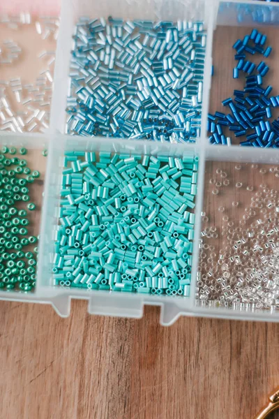 renkli boncuklar ahşap bir masa üzerinde şeffaf plastik kutular