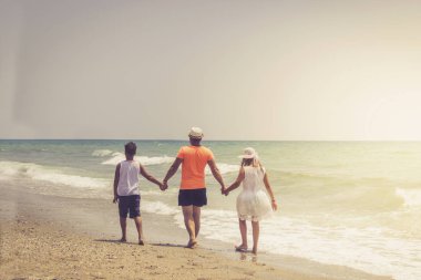 Baba ve çocuklar gün içinde kumsalda eğleniyorlar.