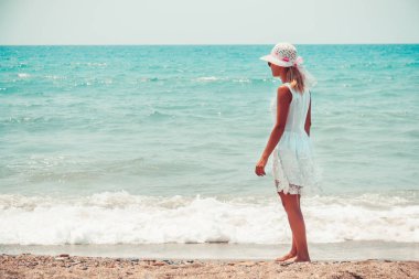 Kumsalda yürüyen yalnız genç kadın.