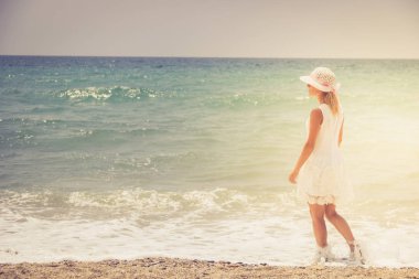 Gün batımı sahilde yürüyen yalnız genç kadın.