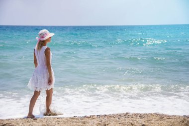 Kumsalda yürüyen yalnız genç kadın.