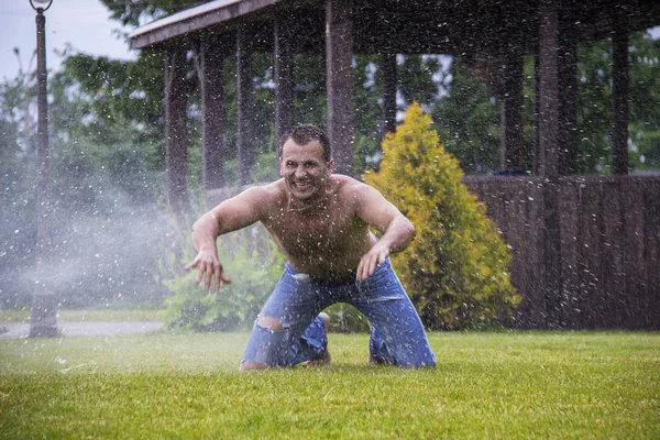 一个快乐的人在喜悦和喜悦飞溅与滴从雨在草 — 图库照片