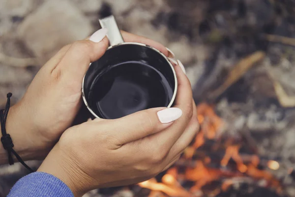 旅行者両手マグカップ魔法瓶から 焚き火の近きます キャンプでマグカップからコーヒーや紅茶を飲む — ストック写真