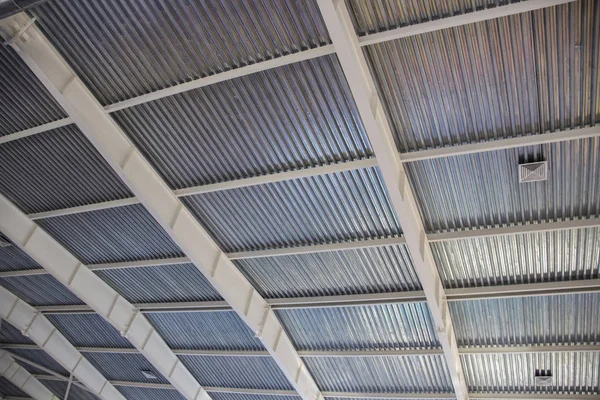 Industrial corrugated metal ceiling structure with metal truss frame.