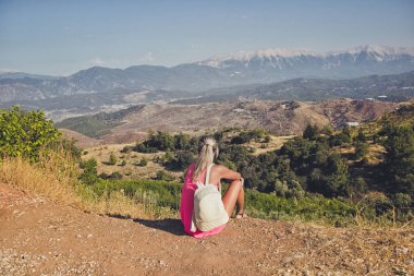 Geniş görünümü dağlar ve ovalar üzerinde seyir uçurumun kenarında oturan genç kadın