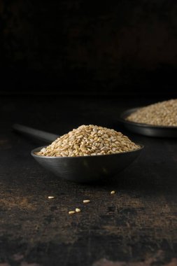 Bir düşük ışık görüntü bir metal kaşık ve susam kopya alanı metniniz için rustik bir zemin üzerine kase