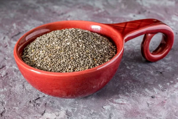 A serving of chia seeds in a red bowl on a stone granite surface