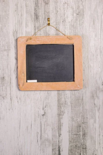 stock image A wooden framed blackboard with chalk hanging on a rustic background with copy space for your text