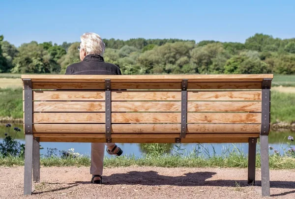 德国尼德萨克森 2015年6月10日 一名单身老年妇女坐在农村的木长凳上 看上去很孤独 — 图库照片
