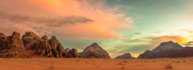 Wadi Rum 'da gün batımı. Turuncu dağlar ve turuncu kum. Ürdün