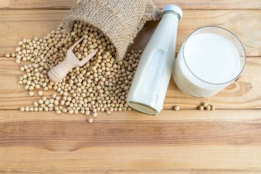 Soya fasulyesi ve soya sütü bir cam ve ahşap masa, üstten görünüm şişesinde