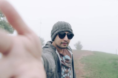 Adam selfie ile dağın tepesinde sisli alarak. Güneş gözlüğü tatil kış sezonu giyen genç adam. Asya seyahat almak selfie doğa açık kavramı.