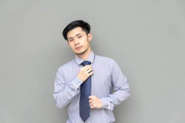 İş adamı gömlek kravat ayarlayın. Onun kravat duran gri arka plan ayarlama giyinme portre Genç Asyalı adam. Gömlekli emin iş adamı
