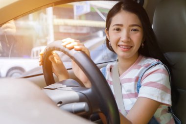 Arabayı kullanan Genç Asyalı kadın görünümlü araba açık gülümseyen etrafında dönerek tekerleği tutar. Araç muayene konsepti