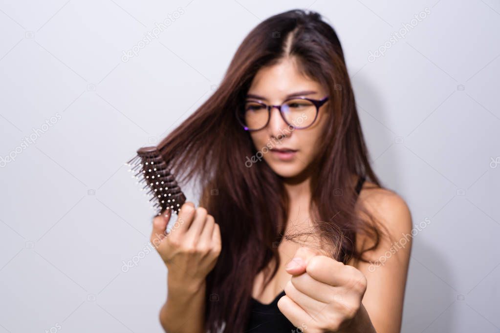 Woman with hair loss holding comb. Young girl losing  hair problem, falling hair on brush healthy medical treatment concept.