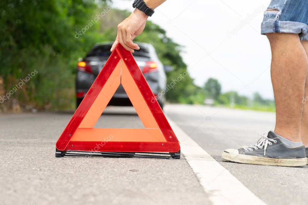 A car breakdown alongside the road, man sets the warning triangle
