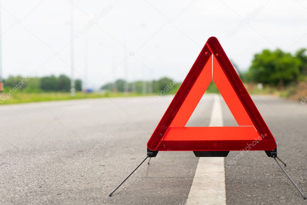 breakdown triangle stands near broken car alongside the road