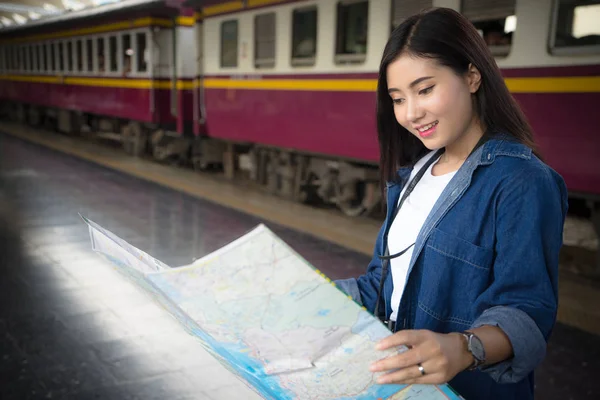 Asian traveler woman looking map at train station find destination