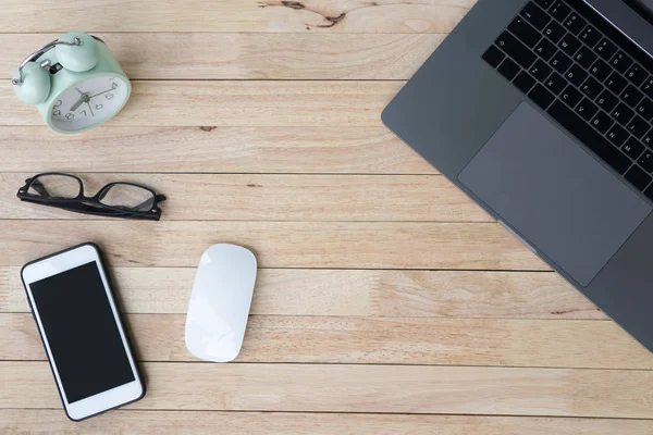 İş ofis büro dizüstü bilgisayar, smartphone, alarmclock ve gözlük. ahşap arka plan üzerinde. Üstten görünüm kopya alanı, düz ile yatıyordu.