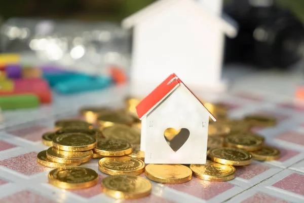 House model on golden coins money, real estate investment for buying property household owner finance concept.