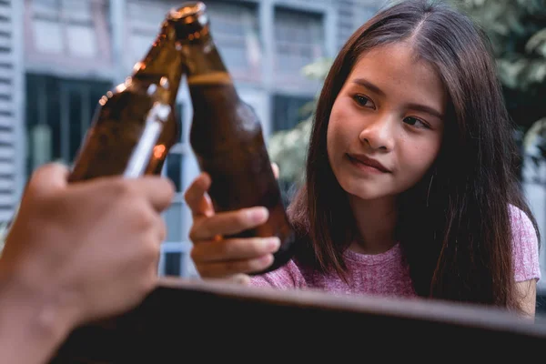 Young woman drinking beer. Party people clanging bottles of beer together, enjoying summer day. Happy friends celebrating and clinking with cold beer bottles.