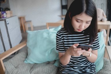 Kafede akıllı telefon kısa mesaj yazarak kadın. Cep telefonu kullaranarak kafede masada oturan genç Asyalı kız. Bağlantı teknolojisi kavramı.