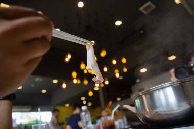 Nadir dilim domuz eti çubuklarla üzerinde kaynar su güveç tutan el. Tay tarzı Barbekü büfesi Tayland. Restoran shabu veya Sukiyaki Japonca veya Kore gıda tarzında. 