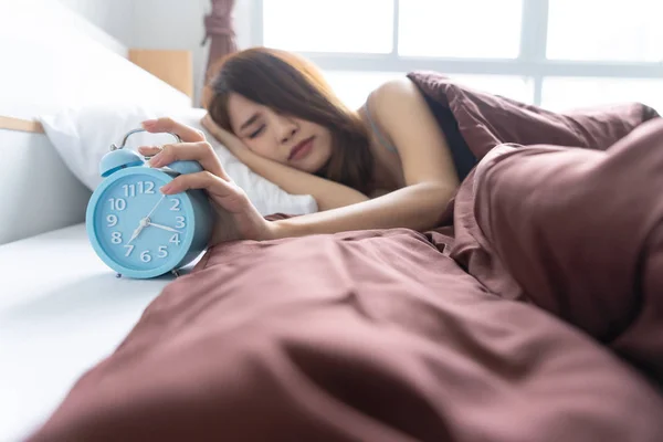 Young woman yawn awakening tired holding alarm clock. wake up early in morning. Girl stop snooze alarm. female waking up sleepy and tired. woman wake up in the morning with alarm clock snooze concept.