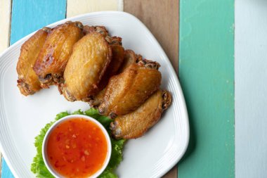 Kızarmış tavuk ve tavuk sosu beyaz tabakta karışık renkli ahşap arka plan üzerinde Üstten Görünüm.