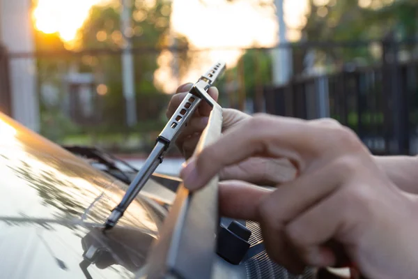 Mannen hand plocka upp bilen vindrutetorkaren. Teknikern föränderliga vindrutetorkare blad. Mekaniker kontrollera, ersätter gamla torkarblad på kundens bil främre fönsterglas. — Stockfoto