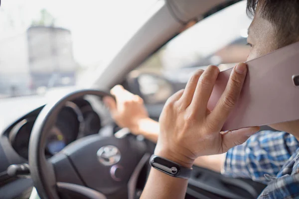 Hombre conduciendo coche y hablando por teléfono móvil. Hombre conduciendo coche sosteniendo el teléfono celular concentrándose en la carretera  . — Foto de Stock