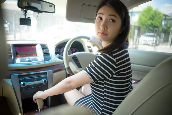 Młoda Azjatka jeździ samochodem i kręci kołem, oglądając się za siebie. jeździć samochód wstecz egzamin koncepcja pojazdu. — Zdjęcie stockowe