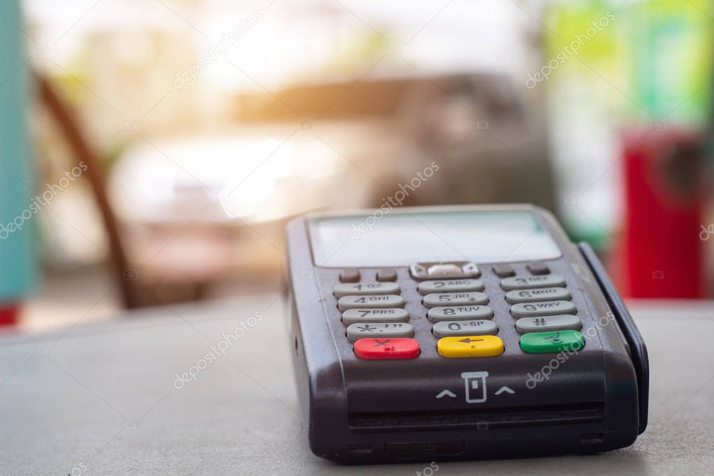 Credit card machine with car refueling petrol at gasoline station in background. Credit card reader payment, buy and sell products & service  Credit Card Terminal or EDC on cashier table.