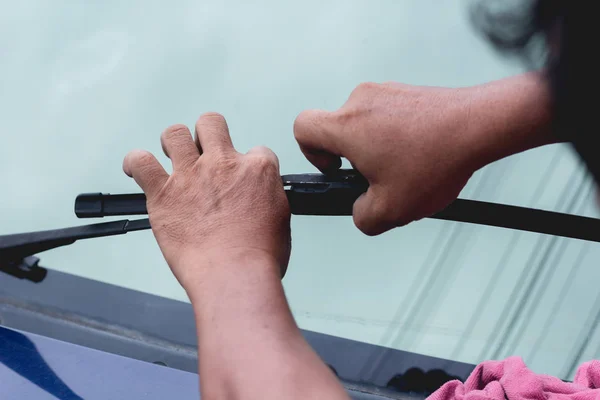 Mechanic replace windshield wipers on car. Replacing wiper blades Change cars wiper blades. Technician Man changing windshield wipers blades on car.