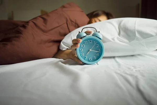 Young woman awakening tired holding alarm clock. wake up early in morning. Girl stop snooze alarm. woman wake up in the morning with alarm clock snooze concept.