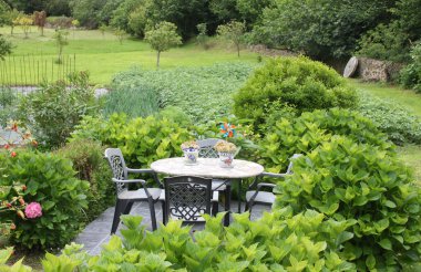 Yeşil bir bahçenin arka planında masa ve sandalyeler