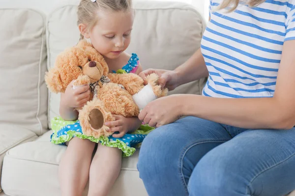 Mom and daughter together playing with teddy bear