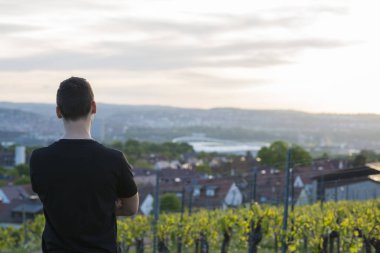 Bağ ayakta ve uzak tepeler üzerinde seyir siyah tişörtlü genç adam
