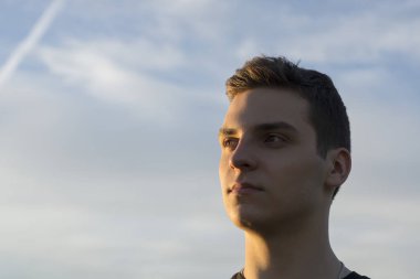 gökyüzü arka plan üzerinde genç yakışıklı bir adam portresi