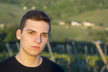 Bir rüya gibi dalgın ifade, baş ve omuzlar açık havada batımına ayakta bakan yakışıklı genç adam