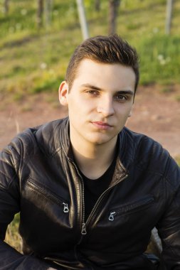 Güzel genç kendine güvenen biri deri ceketli hills yanında oturur