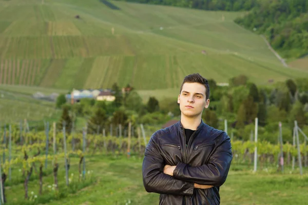 güzel kendine güvenen delikanlı bir deri ceket Üzüm şarapları bir arka plan karşı duruyor