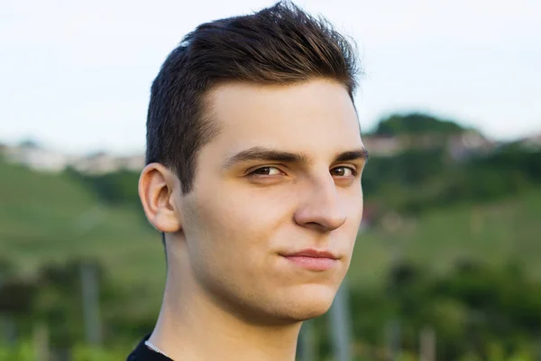 Young adorable man model with a smirk looks into the camera in the evening