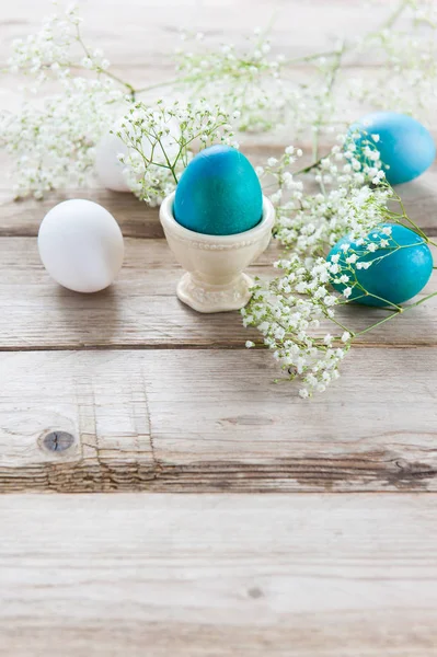 白い繊細な春の花と塗られたイースターエッグ木製のテーブルの上 スタンドで つの卵 — ストック写真