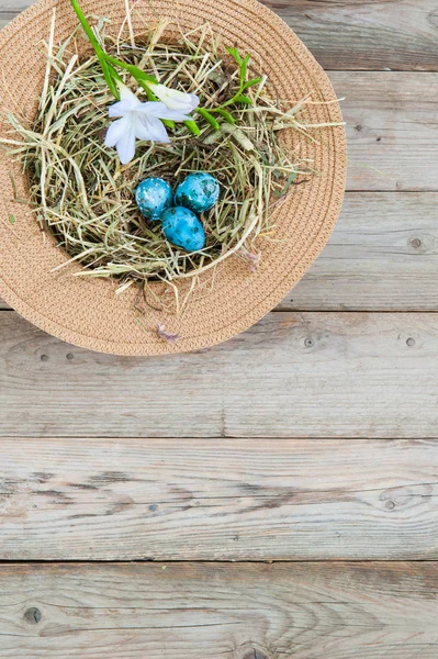 枝編み細工品帽子と花と塗装の斑点を付けられたイースター卵の巣 左上隅に — ストック写真