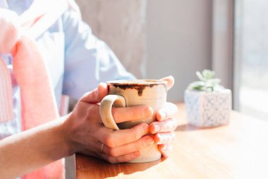 Genç güzel kadın bir kafede kahve içme. Ellerini kapatın. Tonlama.