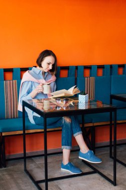 Kahve içme ve gönüllülük a kitap bir kafede genç güzel kadın. Tonlama.