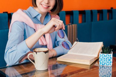 Kahve içme ve gönüllülük a kitap bir kafede genç güzel kadın. Tonlama.