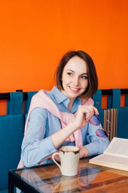 Kahve içme ve gönüllülük a kitap bir kafede genç güzel kadın. Tonlama.