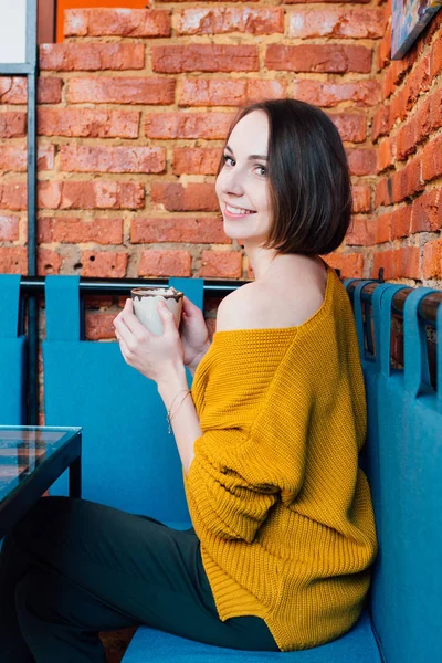 Young beautiful woman drinking coffee in a cafe. Toning.